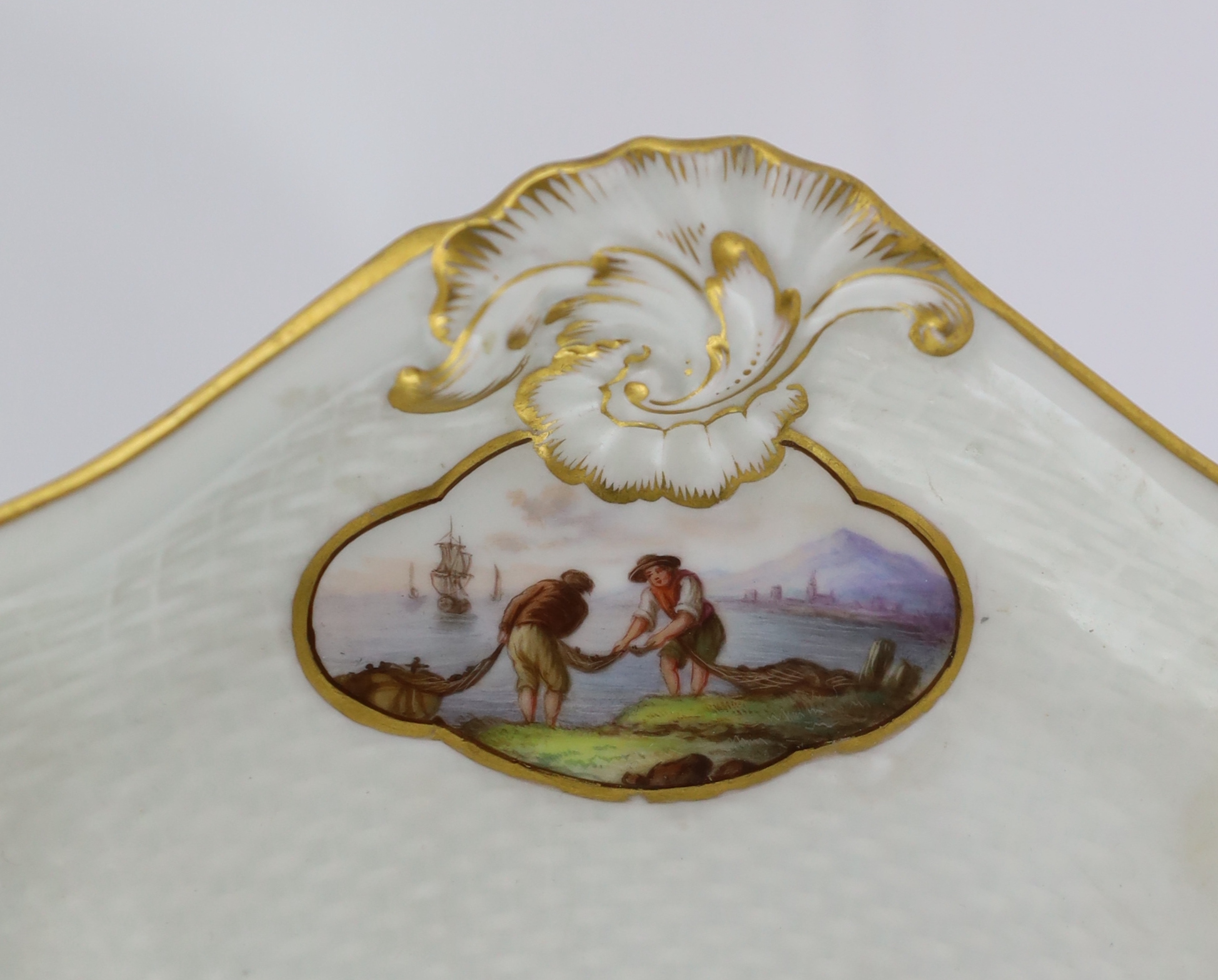 A Meissen porcelain lozenge shaped tray, 19th century, painted with figures in seascapes, ozier moulded ground, underglaze blue crossed swords mark and incised model number 712, 37.7cm wide, broken and restored